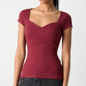 Vinröd topp - Vinröd ribbad topp med snygg v-ringning och korta ärmar från Anna Field. Toppen har en figurnära passform. Perfekt nu till hösten!! Aldrig använd, endast testad. Liten i storlek så sitter som m
