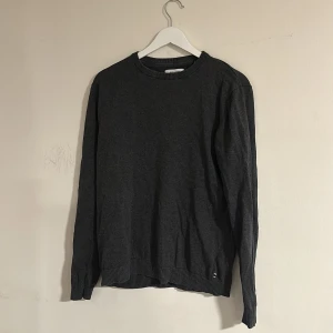 Mörkgrå stickad tröja Jack & Jones - En stilren, grish, mörkgrå stickad tröja från Jack & Jones. Tröjan har rund halsringning, ribbade muddar och är långärmad. Storlek M. Skriv vid minsta fundering🍾🌠