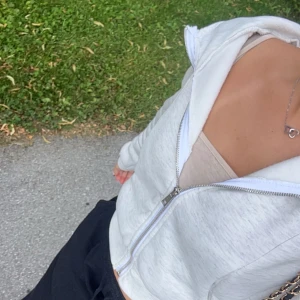 Vit hoodie med dragkedja - Säljer en ljusgrå hoodie med dragkedja framtill och huva. Tröjan har en avslappnad passform och är perfekt att slänga på sig över ett linne eller t-shirt. Mjuk och skön, passar till både jeans och mjukisbyxor.