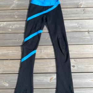Konståknings leggings med blå detaljer - Svarta leggings med bred blå midja och blå diagonala ränder längs benen. Byxorna har även blå kant längst ner vid bensluten. Stretchigt material som sitter tight och är perfekt för vanlig eller konsåknings träning. Defekt visas på bild 3 😇💕