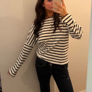 Randig långärmad tröja i bomull - Vit och svart långärmad tröja med  randigt mönster. Där mönstret byter riktning efter trekvarts ärmen. Tröjan har en avslappnad passform och är tillverkad i mjuk bomull. Sparsamt använt 