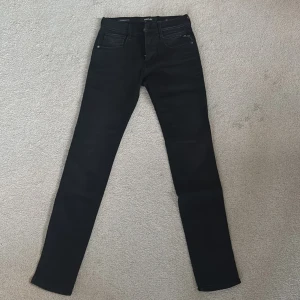 Replay Hyperflex Anbass svarta jeans - Svarta Replay Hyperflex Anbass jeans med klassisk femficksdesign och smal passform. Jeansen är stretchiga och har Replay-logga på myntfickan samt läderpatch bak i midjan. Perfekta för dig som gillar stilrena och bekväma jeans med modern look. Jeansen är aldrig använda utan lappen trillade av och därmed fick jag inte lämna tillbaka de. 