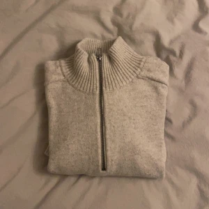 Ljusgrå stickad half zip-tröja - Mysig ljusgrå stickad tröja med ribbad krage och half zip-dragkedja. Perfekt för lager-på-lager och chill dagar. Enkel och stilren design som funkar till det mesta.