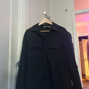 Marinblå Zara overshirt - Säljer denna overshirt ifrån Zara då den är för stor. STRL S men skulle säga passar M beroende på kroppsform! Cond 8/10 har några hål från tidigare ägare men syns knappt vid användning och går såklart att laga därav priset!
