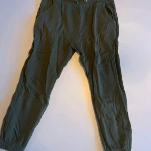 Gröna mjukisbyxor med resår - Mörkgröna mjukisbyxor med resår i midjan och vid bensluten. Byxorna har två sidofickor och är tillverkade i mjukt bomullsmaterial, perfekta för chill dagar. Passar dig som gillar en avslappnad stil.