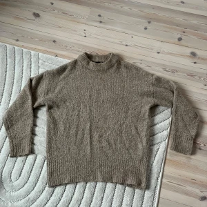 Beige stickad tröja - Mysig beige stickad tröja. Tröjan har ribbade muddar vid ärmslut och nederkant för extra komfort.