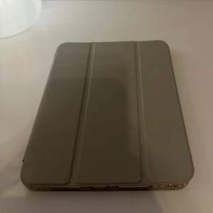 iPad mini  fodral  - Snygg skyddande case i bra skick. Fodralet har stativfunktion och täcker både fram- och baksida. Inga synliga repor eller skador på fodralet. Perfekt för både arbete och underhållning. Den plastiska delen är lite missfärgad, gjort rent den men det går inte bort (synd ej när den är på)