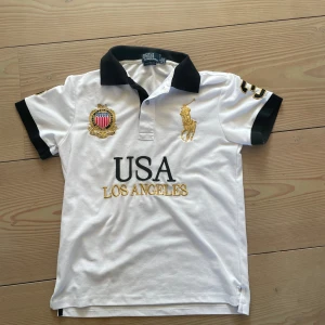 Ralph Lauren Piké S - Tja! Säljer denna feta Vita Chief Keef  pikétröja från Polo Ralph Lauren med svart krage och svarta ärmslut. Broderade detaljer med guld och svart, stor USA Los Angeles-text framtill och stor siffra 3 på ryggen. Storlek S men passar även lite mindre M. Hör av er vid frågor eller funderingar!