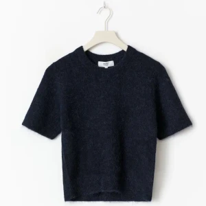 Mörkblå stickad kortärmad topp - Mysig mörkblå stickad med korta ärmar och rund halsringning. Perfekt för lager-på-lager och ger en cool, avslappnad vibe. Materialet är mjukt och fluffigt vilket gör den extra skön att bära. (Lånad bild)