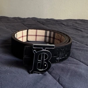 B-rberry bälte med svart logga - Ett svart bälte med svart logga B. Storleken är 110 och passar S och M. 