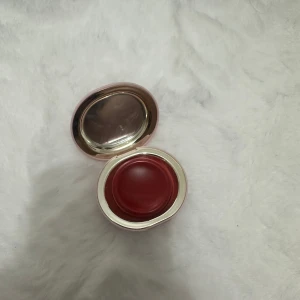 Rare Beauty Melting Blush Nearly Rose - Rare Beauty Melting Blush i färgen Nearly Rose. Krämrouge i en rund, ljusrosa dosa med spegel i locket. Färgen är en mjuk, rosig nyans som smälter in i huden för en naturlig look. Perfekt för dig som gillar ett fräscht glow och enkel applicering.