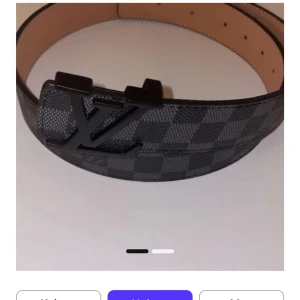 Louis Vuitton bälte - Snyggt Louis Vuitton bälte i svart och grått med klassiskt rutigt Damier-mönster. Bältet har en stilren LV-spänne i svart metall och är tillverkat i äkta skinn med beige insida. Perfekt accessoar för att lyfta din outfit.