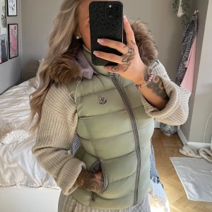 Moncler väst - Moncler väst med avtagbar huva.  Skiftar i olika färger, den ser beige eller mintgrön & lila ut beroende på ljus. Köpte den här på Plick men den har inte kommit till användning.  Vet inte om den har denna färgen för att den är solblekt eller om den ska vara såhär i färgen.   Storlek 1 som motsvarar S  Fint skick i övrigt och supervarm.