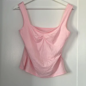 Ljusrosa  linnetopp - Supersöt ljusrosa linnetopp med breda axelband och lätt rynkdetalj framtill. Toppen har slits i sidorna