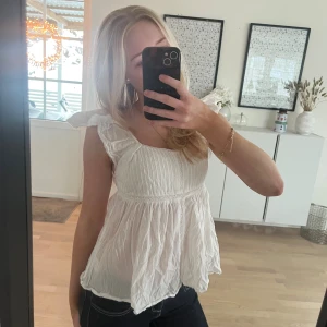 Vit blus med volangärmar - Supersöt vit blus med volangärmar och lätt rynkad, flowy nederdel. Toppen har en söt, fin med smockad överdel och fyrkantig ringning. 