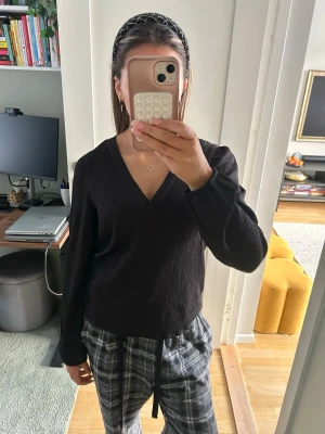 Svart v-ringad blus med lång ärm - Säljer en svart blus med v-ringning och långa ärmar. Blusen har en lätt textur i tyget och en avslappnad passform, perfekt att styla med både jeans och kjol. Enkel och stilren design som funkar året runt. Strl s.