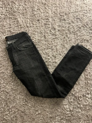 Svarta Lee jeans med skön tvätt - Säljer ett par svarta jeans från Lee. De har rak passform och snygg tvättad look. Passformen är normal och storleken är 28/32.                                                              Hör av dig vid frågor eller prisförslag🫡