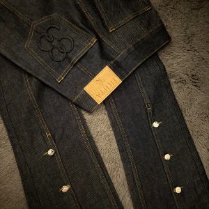 Mörkblå jeansbyxor från Filippa K - Säljer ett par mörkblå jeansbyxor från Filippa K med utsvängda ben och kontrastsömmar. Byxorna har silverfärgade knappar och en snygg patch bak. Materialet är klassisk jeans i bomull och passformen är rak och clean.