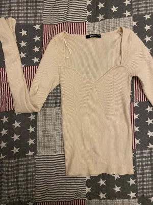 Vit ribbad topp från Gina Tricot - Säljer en vit ribbad topp från Gina Tricot i storlek XS. Toppen har lång ärm, v-ringad skärning och är figurnära i modellen. Materialet är mjukt och stretchigt, perfekt för att styla med jeans eller kjol. I väldigt bra skick knappt använd! 