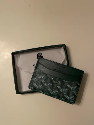 Grön Korthållare Goy4rd - Säljer denna fina gröna korthållare i nytt skick! Box tillkommer och påse! Aldrig använt! Kort följer med! Hör av er vid eventuella frågor! 😊