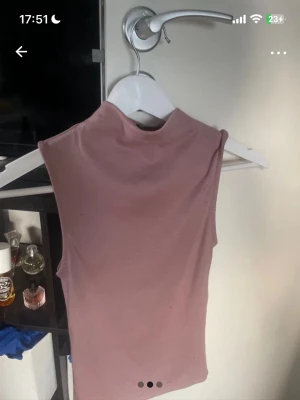 Rosa ärmlös polotopp från Zara - Säljer en superfin ljusrosa polotopp från Zara i storlek S. Toppen är ärmlös och har en hög krage som ger en clean och stilren look. Materialet är mjukt och stretchigt, perfekt att matcha med jeans eller kjol.