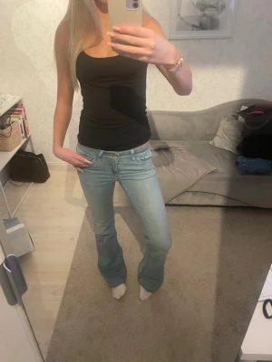 Ljusblå bootcut jeans - Säljer ett par ljusblå jeans från Nelly med bootcut passform och låg midja. Jeansen har snygga rosa broderade detaljer på bakfickorna och klassisk femficksmodell. Tillverkade i mjukt jeansmaterial som sitter skönt och ger en avslappnad vibe. Storlek 36🥰 nypris 600