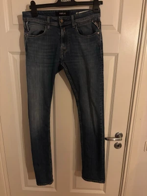 Replay blå jeans - Säljer ett par klassiska blå jeans från Replay med raka ben och normal passform. Jeansen har fem fickor, snygga slitningar och subtila detaljer vid fickorna. Perfekta till sneakers eller boots och funkar året runt. Pris kan diskuteras