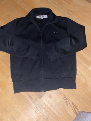 Comme Des Garçons Kofta Svart - En svart kofta med krage som man kan ha upp eller vika ner. Den är i jättefint skick i storlek S. Hör gärna av er om ni är intresserade!