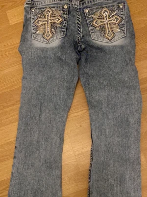 Miss me  jeans med broderade fickor - Säljer ett par blå jeans från miss me med unika broderade kors och paljettdetaljer på bakfickorna. Jeansen har normal passform, raka ben och snygg tvättad look. Materialet är klassisk jeansbomull och detaljerna gör dem riktigt speciella. Säljer för att dem är lite förstora i midjan annars inga hål eller skador eller liknande❤️