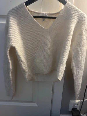 Vit stickad v-ringad tröja H&M - Mysig vit stickad tröja från H&M i storlek XS. Tröjan har en djup v-ringning och långa ärmar. Perfekt för lager på lager och passar till allt. Ribbad struktur som ger en snygg och enkel look.