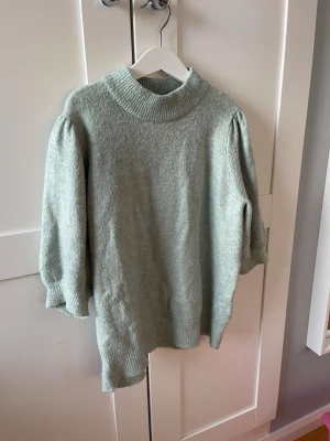 Ljusgrön stickad tröja från ONLY - Supermysig ljusgrön stickad tröja från ONLY med puffiga trekvartsärmar och hög ribbad krage. Perfekt för lager-på-lager och chill dagar. Tröjan har en relaxed fit och är riktigt skön mot huden.