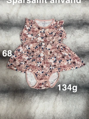 Blommig rosa babyklänning med inbyggd body strl 68 - Supersöt babyklänning med inbyggd body från Polarn o pyret  i storlek 68. Klänningen är rosa med blommigt mönster i vitt, blått och brunt, har lång ärm och inbyggd body med knappar. Perfekt för små fashionistas som gillar färg och mönster.🌸 Sparsamt använd. Storlek 68