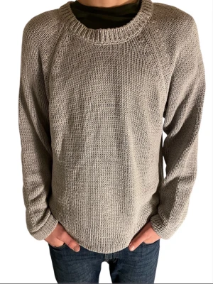 Grå stickad tröja med knappar - Säljer en grå stickad tröja med grovstickad känsla och rund hals. Tröjan har långa ärmar och tre stora svarta knappar på sidan som snygg detalj. 