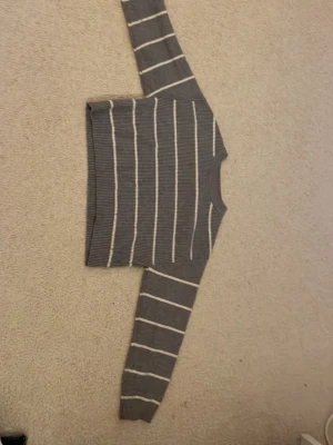 Gråvit randig stickad tröja Zara - Säljer en grå stickad tröja från Zara med vita horisontella ränder. Tröjan har rund halsringning och långa ärmar. 🩷