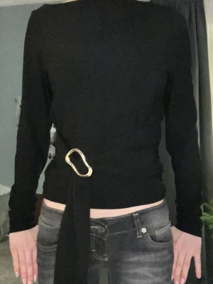 Svart tröja från Zara - Säljer en svart långärmad omlottopp med snygg guldfärgad metallring i midjan. Super fint tröja och har nästan inte används!! Storlek är XS, men passar också för S. Priset går att diskutera 💛