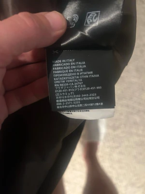 Brun sammet jacka från Prada - Exklusiv brun jacka från Prada i mjuk bomullssammet. Jackan har klassisk krage, raka ärmar och dragkedja framtill. Ikonisk metallogo på bröstet och två sidofickor. Perfekt för dig som vill ha en clean och lyxig look.