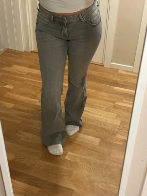 Grå bootcut jeans - Säljer ett par gråa bootcut jeans med klassisk femficksmodell och normal passform. Jeansen har en snygg tvättad look och är tillverkade i mjukt denimtyg. Perfekta för dig som gillar en avslappnad men ändå trendig stil. Har använt 1 gång och lappen bak på jeansen är klippt!