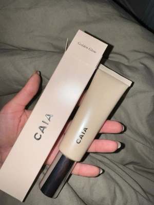 CAIA Golden Glow liquid highlighter - Liquid highlighter från CAIA i nyansen Golden Glow. Kommer i en stilren beige tub med silvrig pump och lock. Ger en fräsch och naturlig finish med glow. 