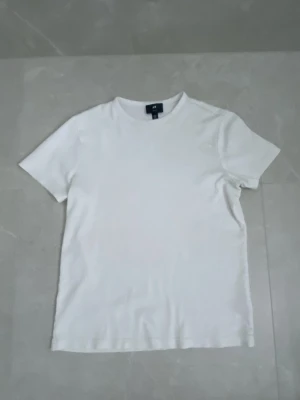 Vit ribbad t-shirt från H&M Slim Fit - Vit t-shirt från H&M i slim fit-modell, tillverkad i ribbad bomull. Klassisk rund hals och korta ärmar. Enkel och clean design som funkar till allt, med mjukt material och snygg passform.