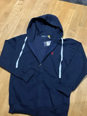 Ralph Lauren zip up M - En lite schystare Ralph Lauren full zip, färg mörk blå. Nyskick helt oanvänd, skriv om du har frågor!