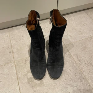 Svarta mocka stövletter med dragkedja - Snygga svarta boots i mocka med dragkedja på sidan. De har en bekväm klack och rundad tå, vilket gör dem perfekta för både vardag och fest. Passar bra till jeans eller klänning.
