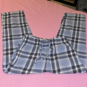 Blårutiga mjukisbyxor/pyjamas  från lager 157 - Blårutiga mjukisbyxor från 157 med dragsko i midjan. Byxorna har ett klassiskt rutmönster i blått, vitt och svart och är tillverkade i mjukt bomullstyg. Perfekta för chill dagar hemma eller som mysplagg.