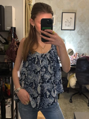 Blåmönstrad ärmlös linnetopp - Säljer en luftig och flowy ärmlös linnetopp med blått och vitt mönster. Toppen har öppen rygg🥰 Köpt secondhand