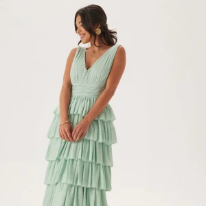 Mintgrön långklänning - Bubbleroom - Helt ny, endast testad 1 gång. Supersnygg mintgrön långklänning från Bubbleroom med flera lager volanger och v-ringad både fram och bak. 