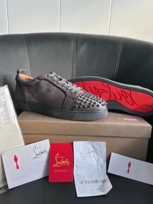 Christian Louboutin grå mocka sneakers - Snygga grå skor från Christian Louboutin i mjuk mocka med ikoniska röda sulor och coola nitar där fram. Helt nya men har testad de ute så använda 1/2 gånger. Säljer pågrund av att det inte riktigt är min stil. storlek  41 men passar 42. Skick 10/10 pris kan diskuteras vid snabbafärr. Allt på bild medföljer!
