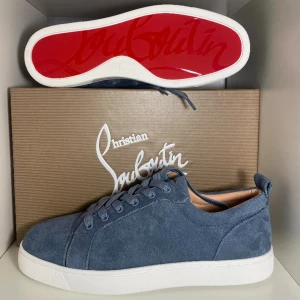 Blå mocka sneakers Christian Louboutin - Snygga blå sneakers från Christian Louboutin i mjuk mocka med klassisk vit platt sula och ikonisk röd undersida. Skorna har rund tå, snörning och diskret branding på insidan. Skorna är helt oanvända och kommer med original skolåda samt kvitto. Skorna passar fötter i storlek 45 och i 46. Bolla gärna priset med mig. Dm för frågor!