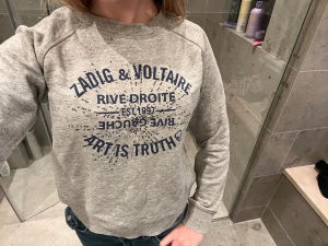 Grå sweatshirt Zadig & Voltaire - Snygg gråmelerad sweatshirt från Zadig & Voltaire ⚡️⚡️med blått tryck framtill: 'Rive Droite', 'Art is Truth' och coola detaljer. Tröjan har rund halsringning, långa ärmar och är gjord i mjukt material, perfekt för en avslappnad streetstyle.🍒☎️