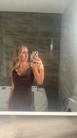 Mörkbrun satin klänning med cowlneck - Säljer en elegant mörkbrun klänning i satin med snygg cowlneck och smala axelband. Klänningen har en slank siluett och är perfekt för dig som gillar minimalistisk och stilren design. Passar dig som vill ha en enkel men chic look. Passar xs och s. Köpte utomlands