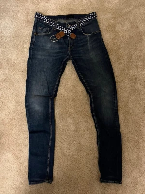 Tiger of Sweden mörkblå jeans  - Snygga mörkblå jeans från Tiger of Sweden med klassisk femficksdesign och slitningar för en cool look. Modellen är slim och är perfekt för dig som gillar stilrena och moderna jeans. Bälte ingår Inte!! W32L34 