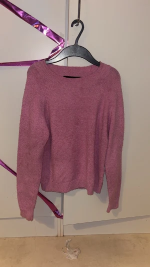 Rosa stickad tröja från Vero Moda - Mysig rosa stickad tröja från Vero Moda i storlek XS. Tröjan har rund halsringning, ribbade muddar och långärmad passform. Perfekt för dig som gillar en enkel och chill look med lite färg. Superenkel att matcha med jeans eller kjol.